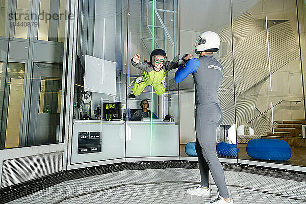 Instructor assisting girl at indoor sky diving center