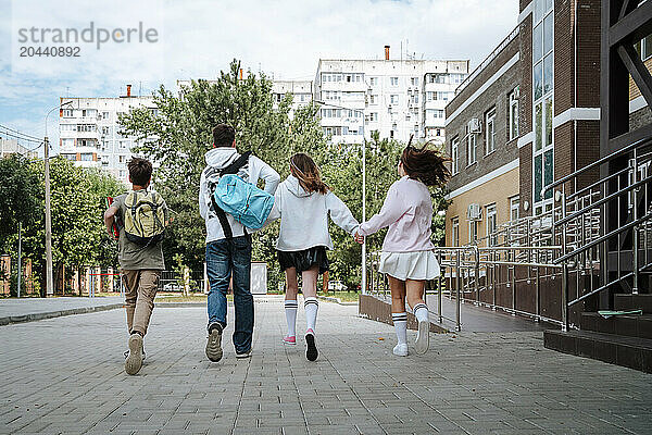 Teenage boys and girls running side by side at schoolyard