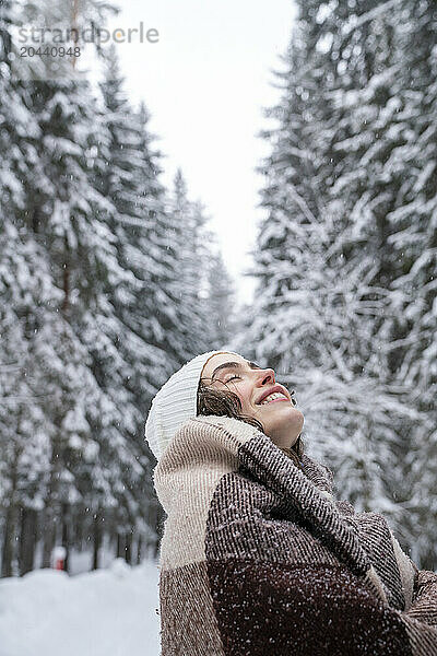 Carefree woman wrapped in blanket at winter forest