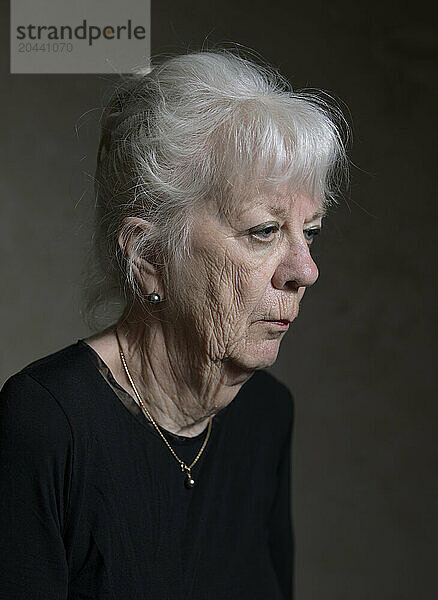 Senior woman with white hair against black background