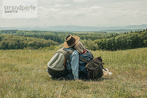 Couple sitting in meadow and enjoying vacation on mountain