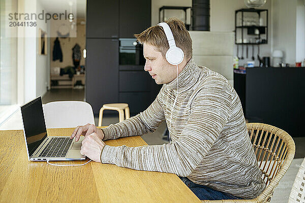 Man in headphones working on laptop at home