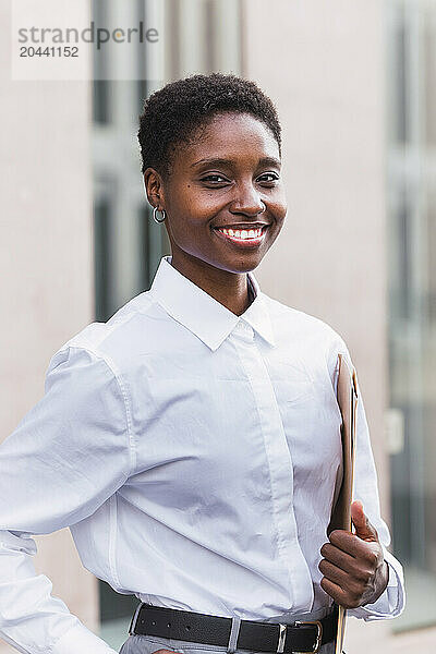 Smiling businesswoman standing with document at office park