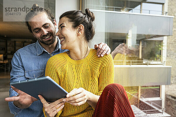 Happy young woman sharing tablet PC with boyfriend at home