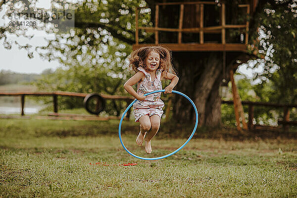 Playful girl playing with hoop near tree house