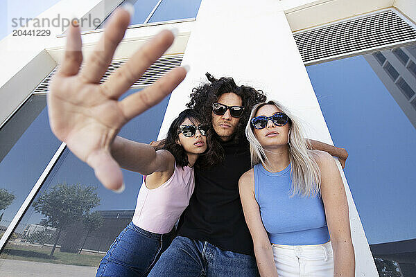 Friends wearing sunglasses and posing in front of university building