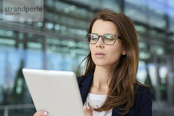 Businesswoman wearing eyeglasses using tablet PC at airport