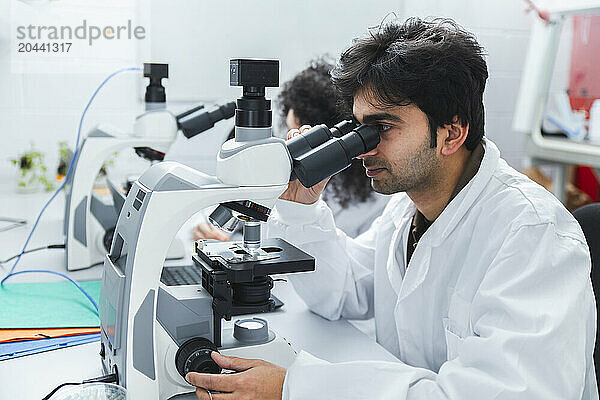 Scientist analyzing sample with microscope in laboratory