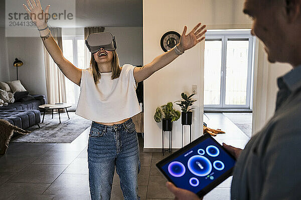 Happy woman wearing virtual reality simulator with man holding tablet PC