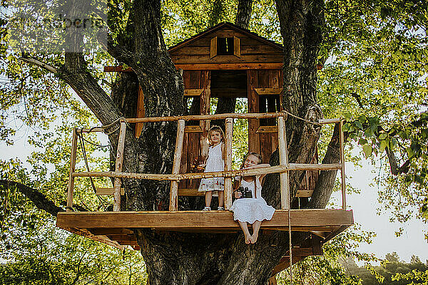 Sisters on tree house in garden