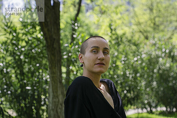 Confident woman with shaved head in park