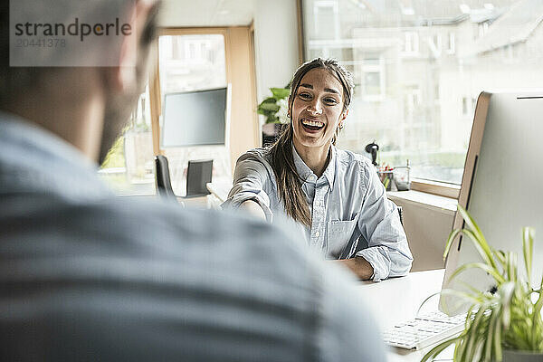 Cheerful businesswoman communicating with coworker at office