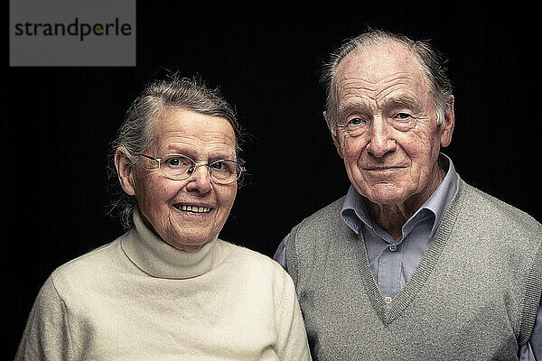 Senior couple smiling against black background