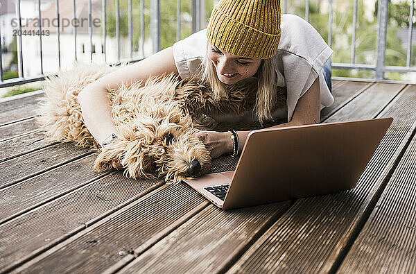 Happy young woman having fun with dog on balcony