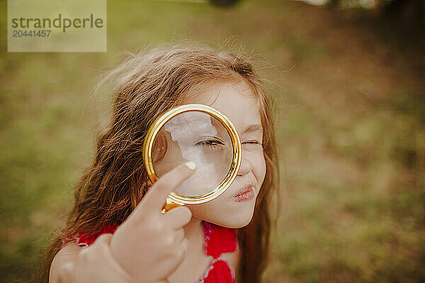 Cute girl looking through with magnifying glass