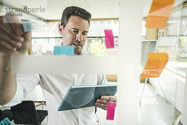 Confident mature businessman using tablet PC brainstorming strategy at office