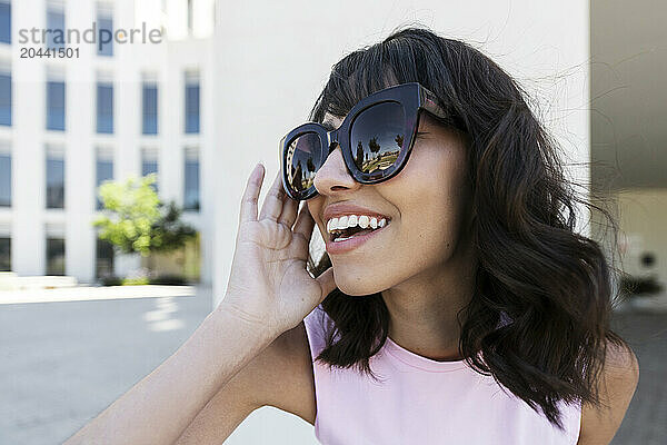 Happy woman with bangs wearing sunglasses at college campus