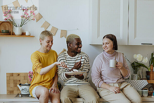 Young friends enjoying breakfast on kitchen counter at home