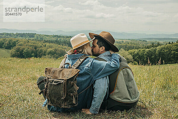 Couple sitting on mountain and kissing each other