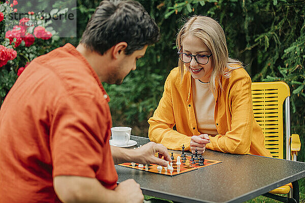 Happy couple playing chess in garden