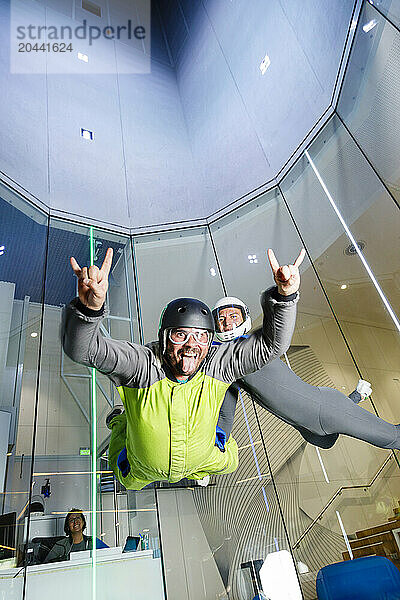 Man sticking out tongue and enjoying skydiving with instructor