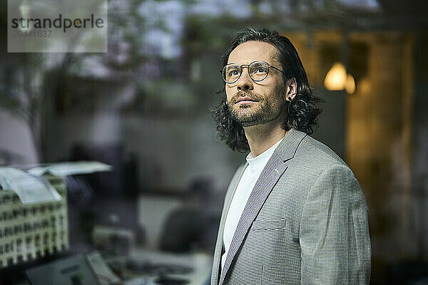 Thoughtful mature businessman looking out through office window