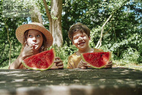 Boy and girl enjoying watermelon in summer