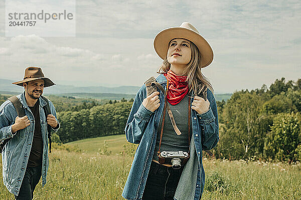 Smiling man and woman wearing denim shirts walking on mountains