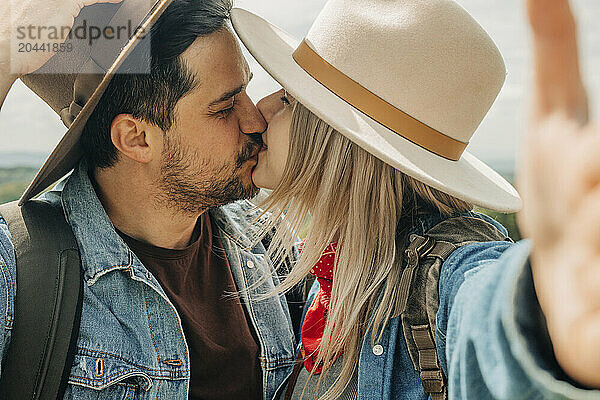 Cheerful couple kissing and taking selfie