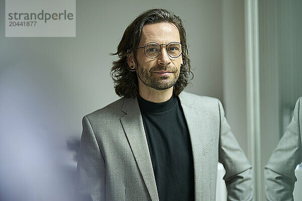 Confident businessman wearing eyeglasses standing at office