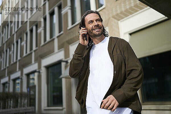 Mature man talking on smart phone in front of modern building