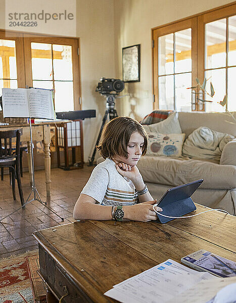 Boy looking at digital tablet at table in living room