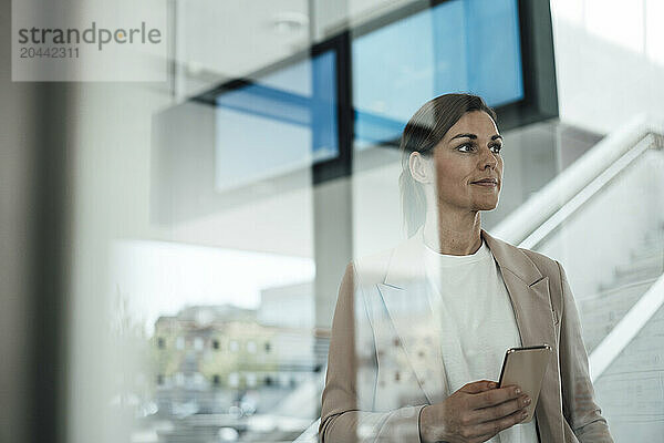 Businesswoman holding smart phone and standing at airport