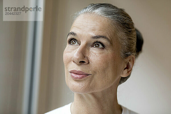 Retired senior gray haired woman looking up at home