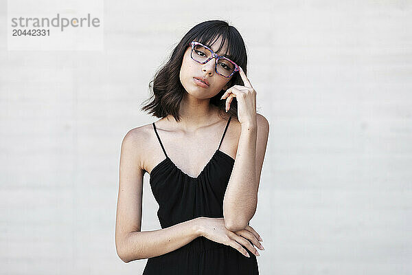 Confident young woman wearing eyeglasses in front of white wall