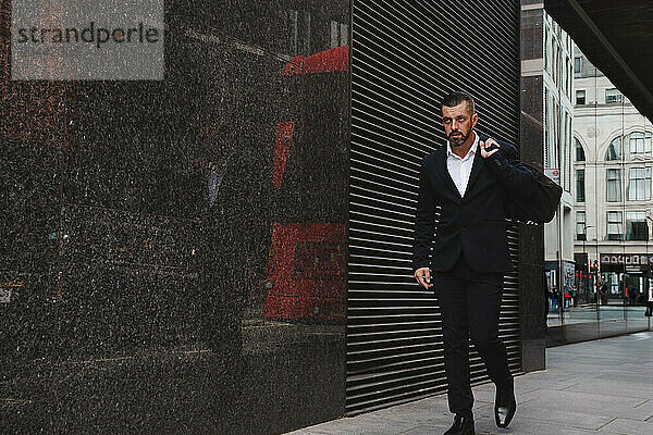 Businessman holding bag and walking near building