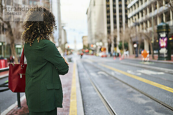 Businesswoman with curly hair standing on street in city