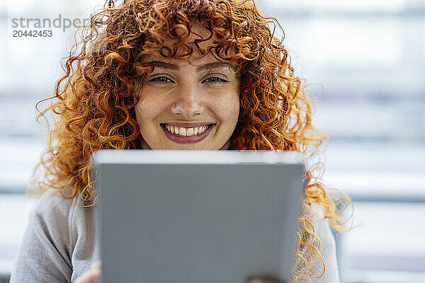 Smiling redhead young woman using tablet PC