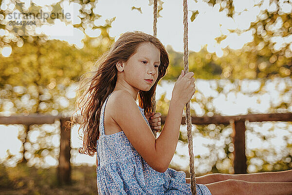 Redhead girl sitting on swing at garden