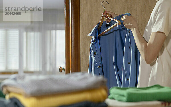 Mature woman hanging ironed shirt on coathanger at home