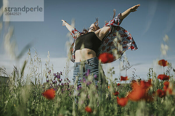 Carefree woman with arms outstretched in meadow