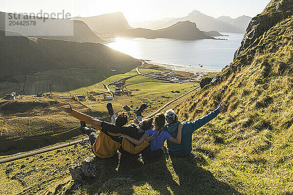 Happy friends sitting on cliff at Lofoten and Nordic islands in Norway