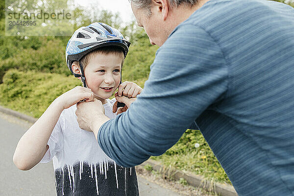 Father helping son to adjust cycling helmet