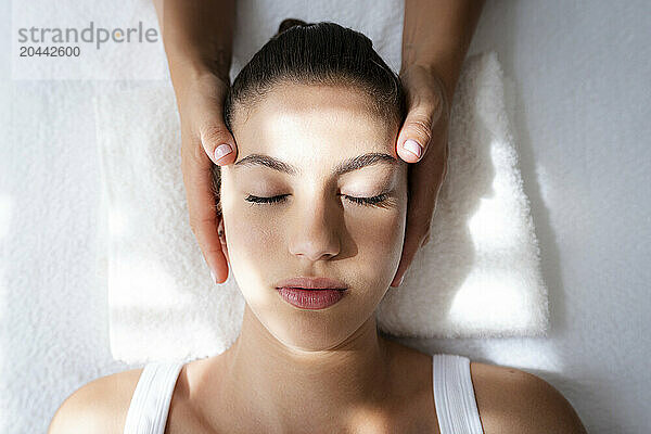 Hands of osteopath massaging teenage patient's head in rehabilitation center