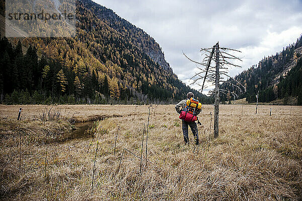 Senior man with backpack standing in front of mountains