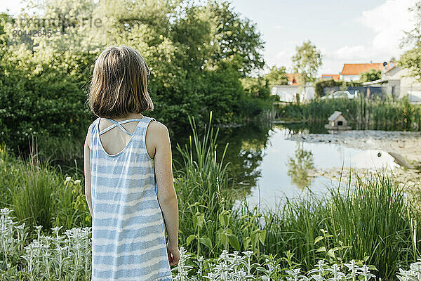 Young girl standing and enjoying near pond