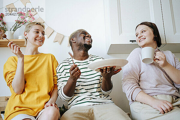 Happy friends enjoying breakfast sitting in kitchen