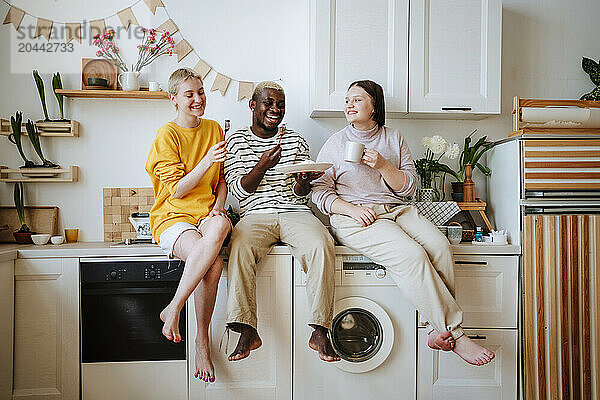 Friends enjoying breakfast sitting on kitchen counter