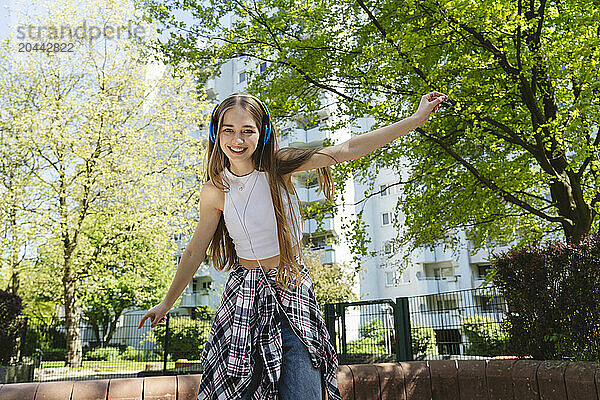 Happy teenage girl dancing and listening to music through headphones