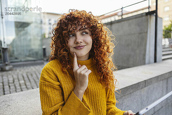 Smiling thoughtful redhead young woman with curly hair looking away